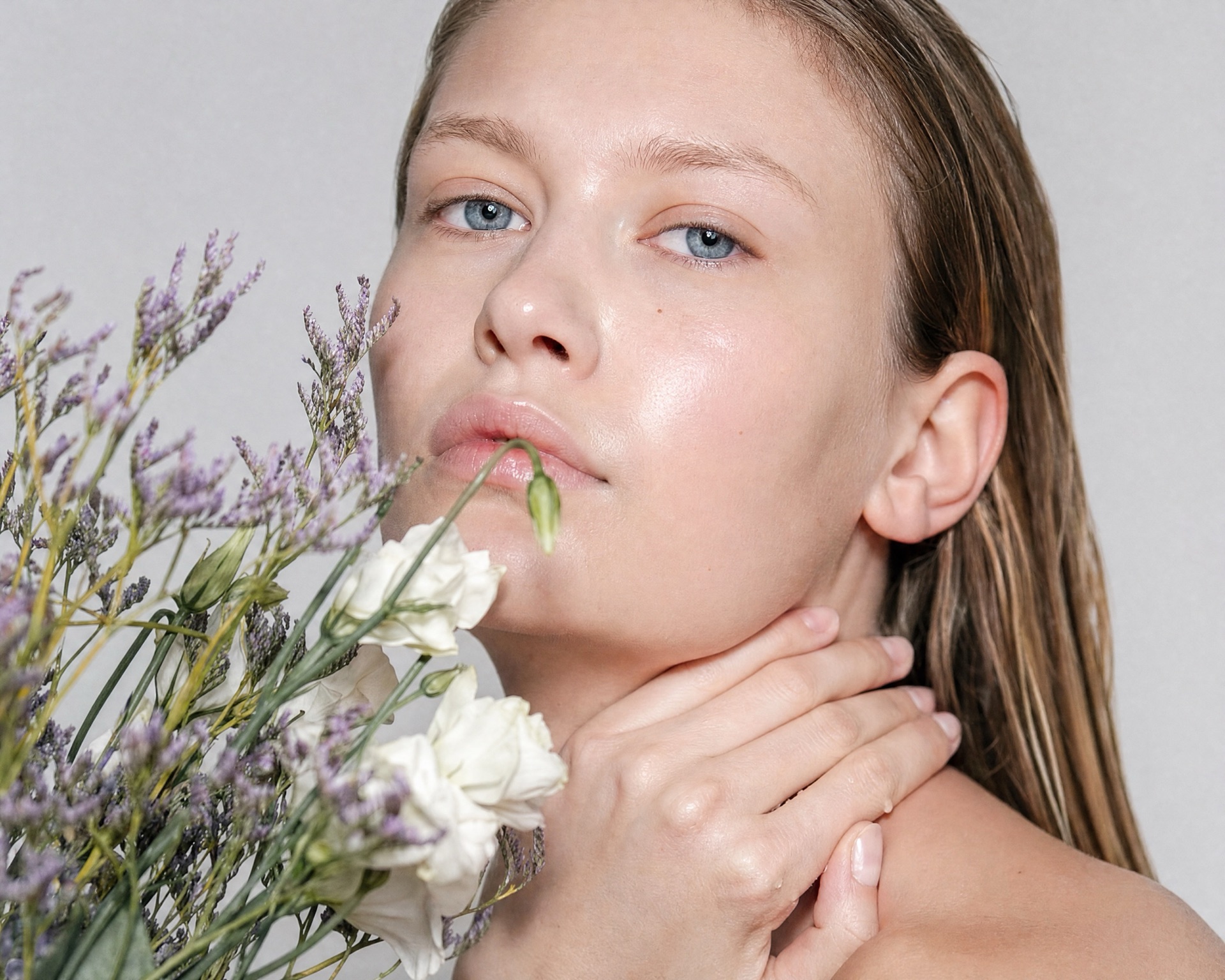 Woman holding pale wildflowers near her face